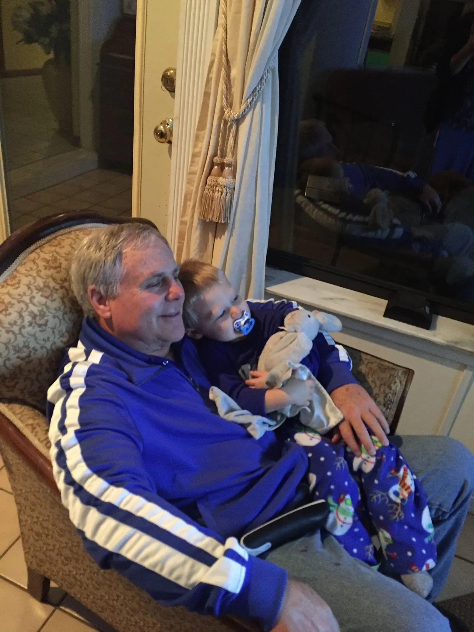 Man cuddling child with stuffed bunny in chair