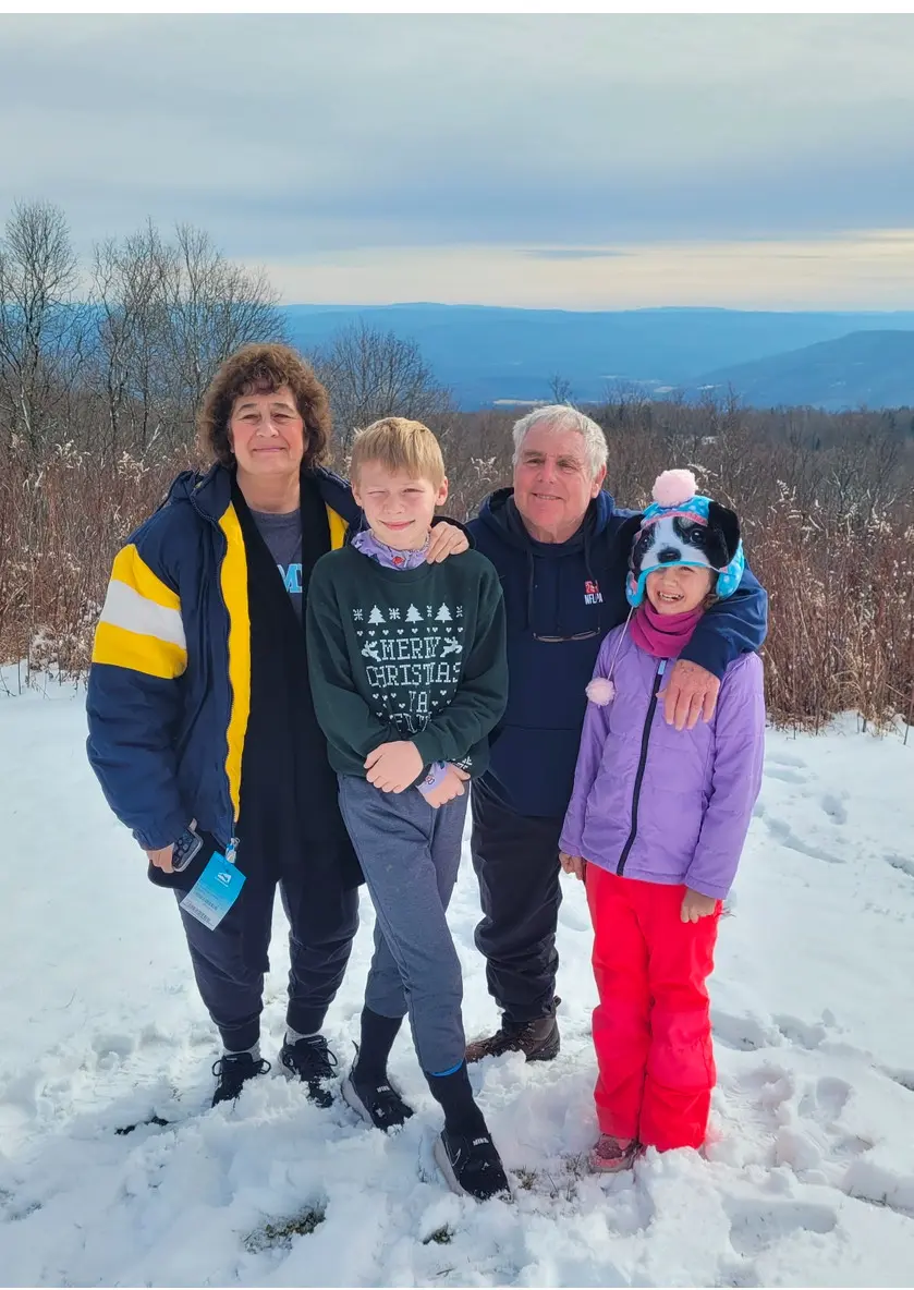 Four people smiling on snowy mountain overlook