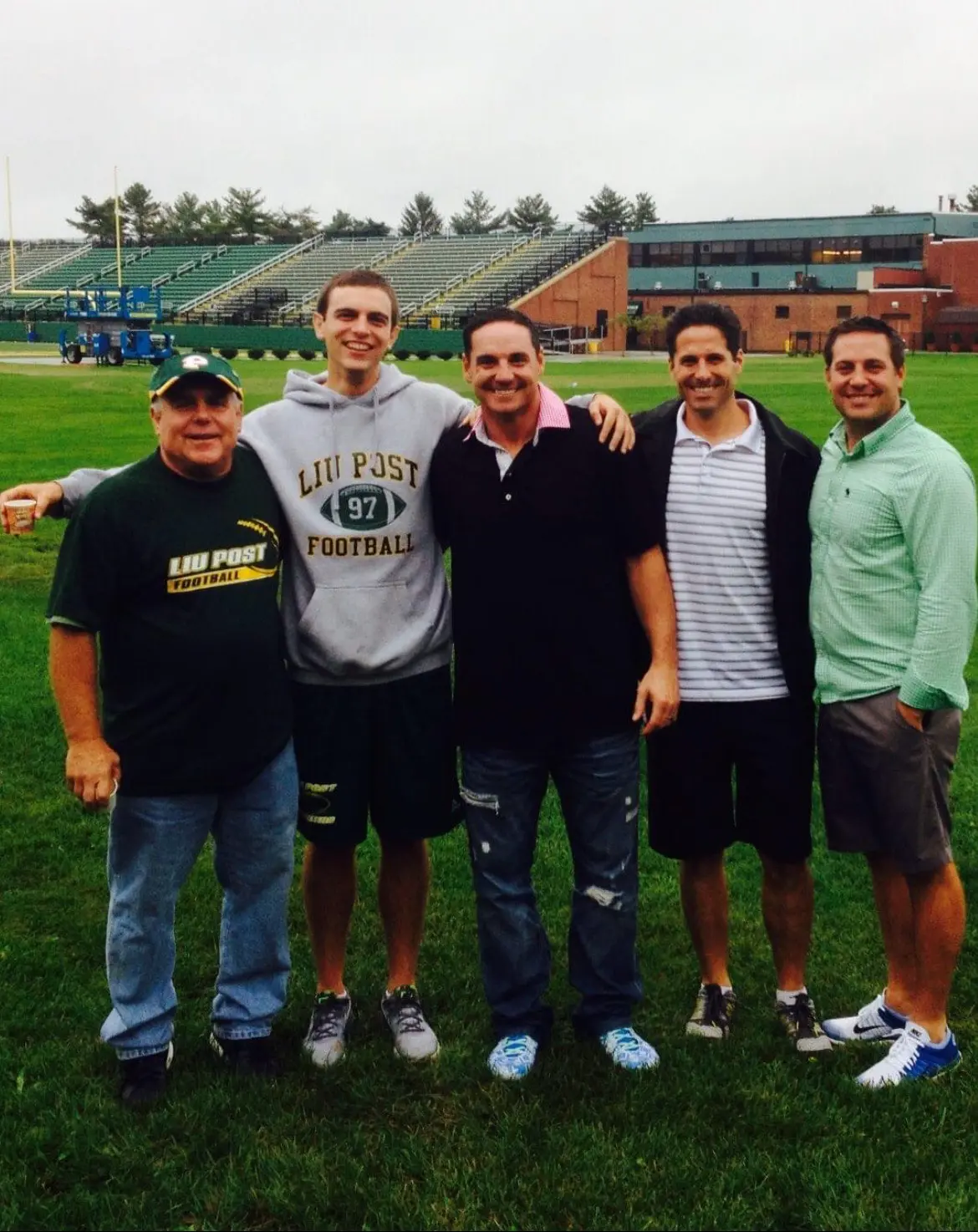 Five men posing on college football field