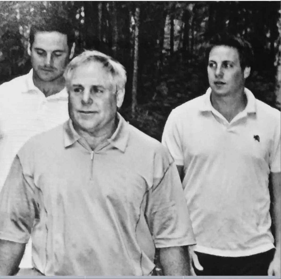 Three men in polos walking through woods