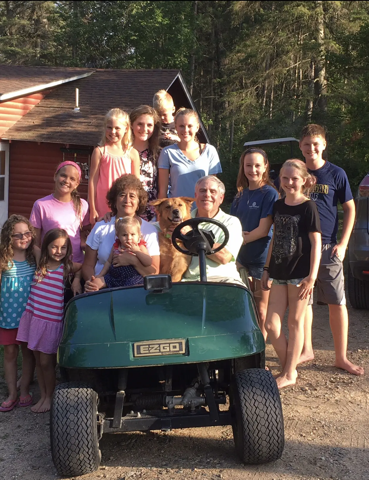 Large family with dog around golf cart